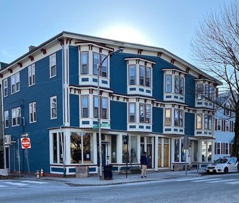 A photograph of 292 – 298 Broadway, Cambridge, where John McAdams attempted to leave his apartments vacant. The building is three stories tall, painted tastefully and elaborately, with glass front shop windows.
