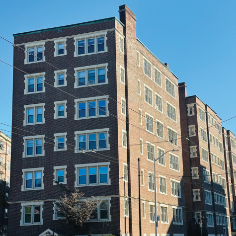 A sidewalk view of 19 Garden St., Cambridge, Mass., which is a multi-story brick apartment complex on a busy city street.]