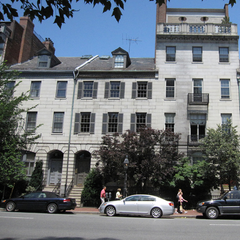 A street-level photograph of the building that encompasses 70-75 Beacon Street, Massachusetts. It is a multi-story gray stone building with dark gray slate roof, and trees along the sidewalk.]