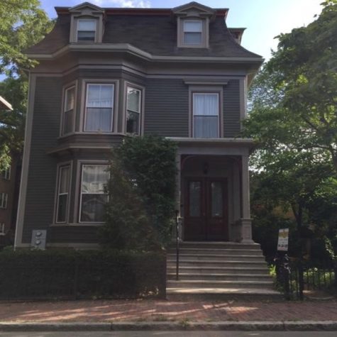 A small, hand restored two family building sits with wood clapboard siding, steps up to two front doors and mansard roof.