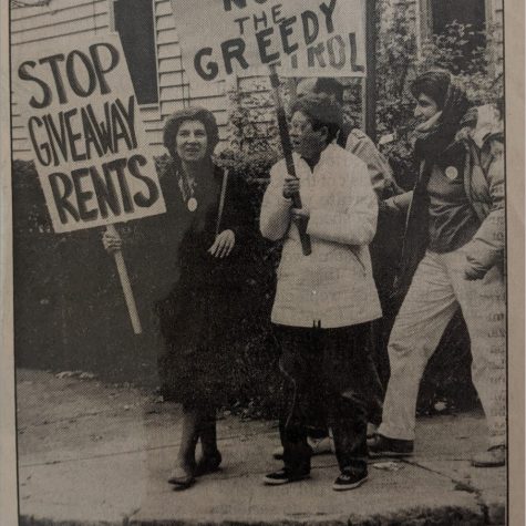 One marcher holds a sign Stop Giveaway Rents. Another, Peggy Wolynes, holds a sign Housing For the Needy Not the Greedy. Two more stand behind them.