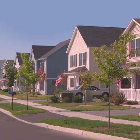 photo of a modern street lined with large single-family homes of similar two-story design, on a bright, clear day.